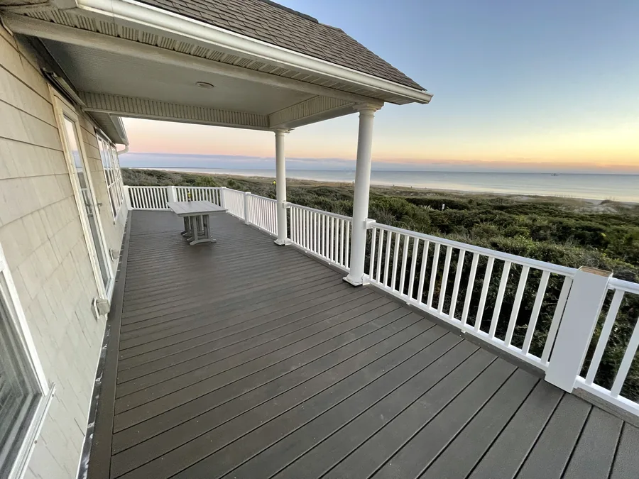 Rebuilt upper oceanfront deck in Oak Island with white railings, looking out over the dunes to the ocean.