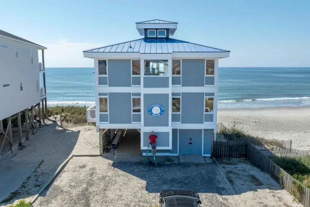 After: the same oceanfront rental finished in blue siding and white trim, seen from above.