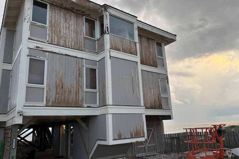Before: oceanfront rental with weathered, peeling siding and faded trim, ahead of re-siding.