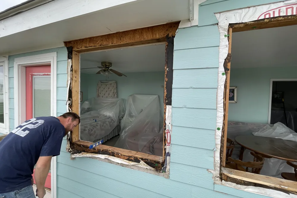 Before: two windows pulled from a deck-level wall in Caswell Beach, with rotted framing exposed around the openings.