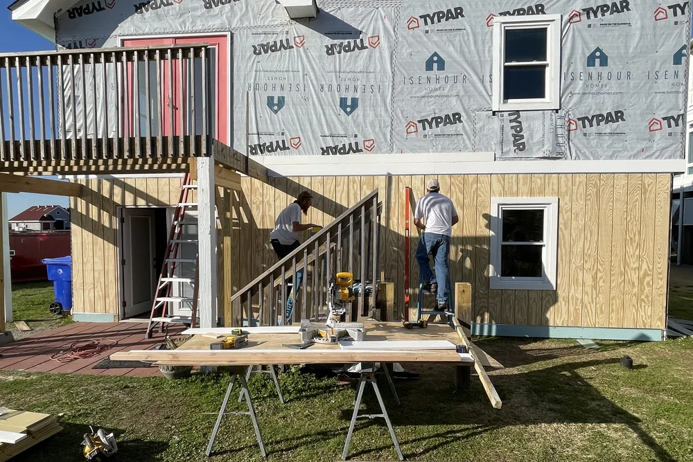In progress: crew at work on the rebuilt lower-level wall in Caswell Beach, with the upper floors in house wrap.