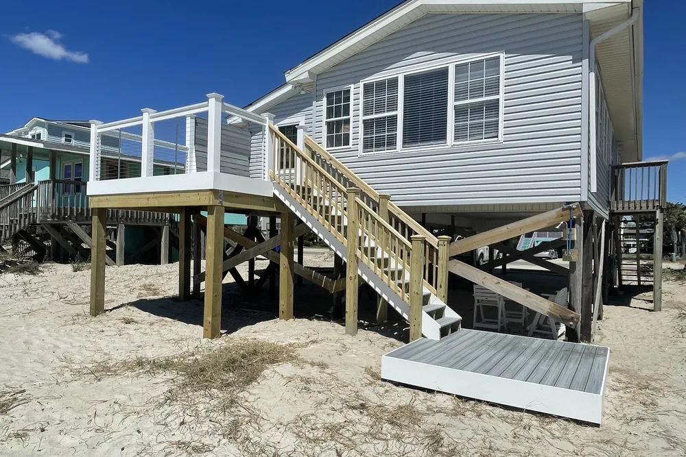 Raised beach cottage in Oak Island with the deck extension, stairs, and landing built out over the sand.