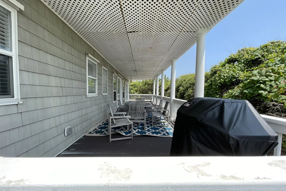 Before: covered lower level of a two-story oceanfront deck in Oak Island, with a lattice ceiling and worn rail cap.