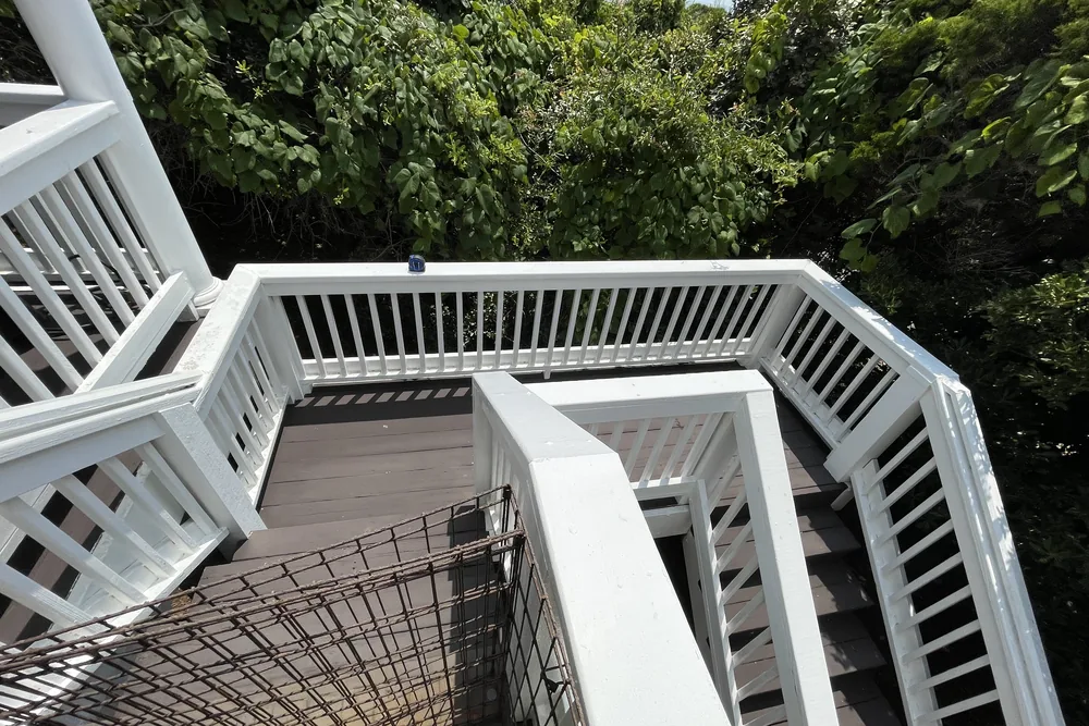 Before: stairs and landing of a two-story deck in Oak Island, seen from above, ahead of the deck and stair rebuild.