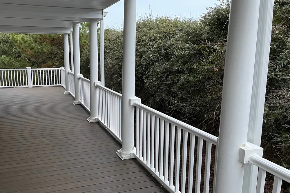 After: rebuilt lower deck in Oak Island with white columns and railings under the new under-deck drainage ceiling.