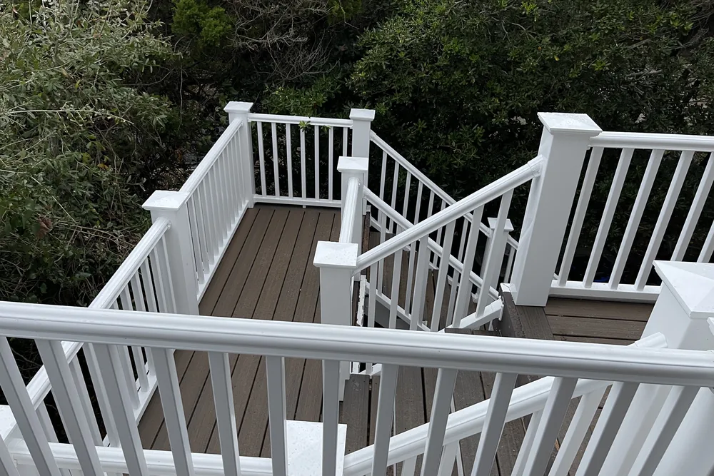 After: rebuilt stairs and landing of the two-story deck in Oak Island, with white railings and composite treads.
