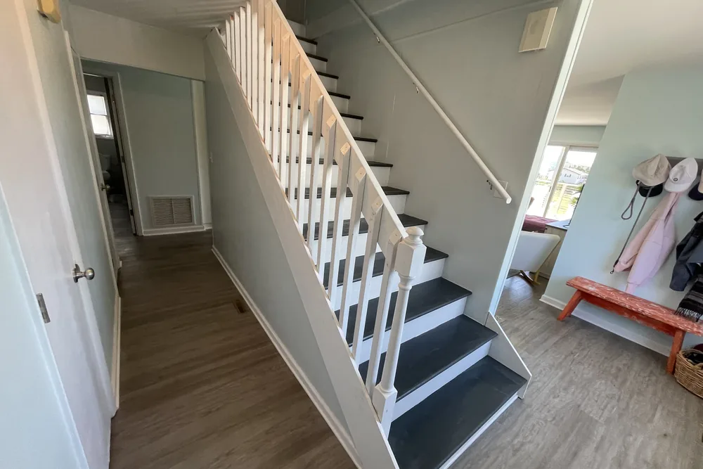 Rebuilt interior stair in Oak Island with white balusters and risers, dark treads, and a wall-mounted handrail.